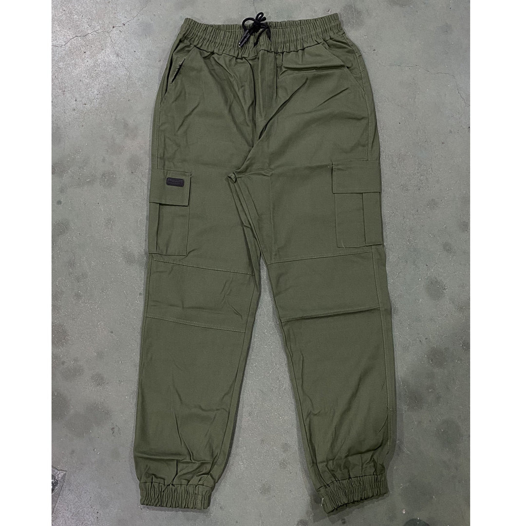 Green pants laid flat on a gray concrete surface