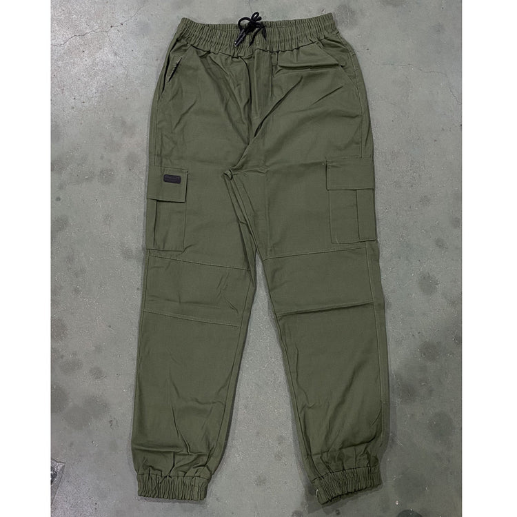 Green pants laid flat on a gray concrete surface